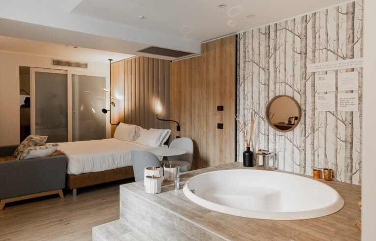 Camera d'hotel con letto, vasca e area salotto elegante.