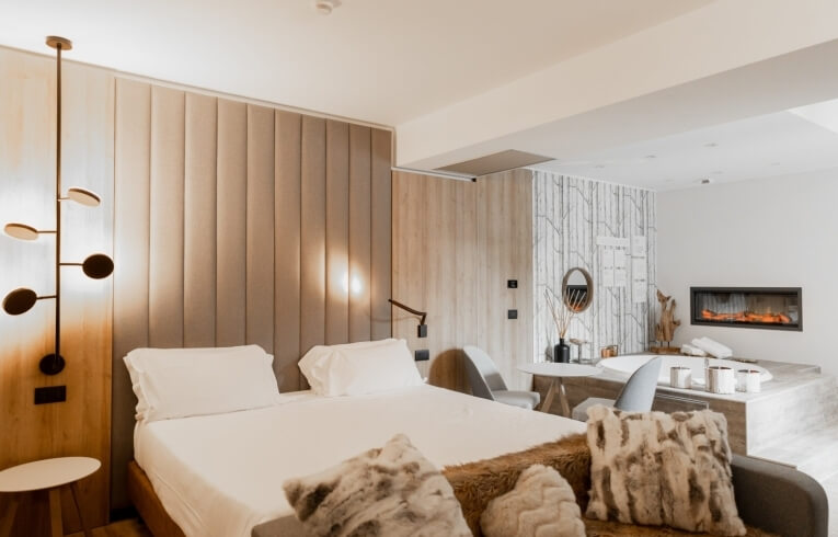 Camera d'hotel con letto grande, lampada moderna e area spa.
