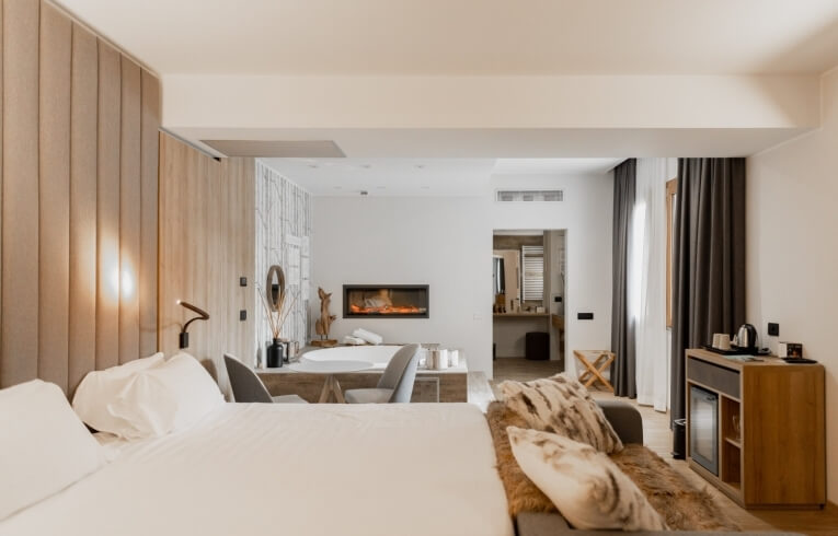 Camera d'albergo con letto, vasca, camino e decorazioni eleganti.