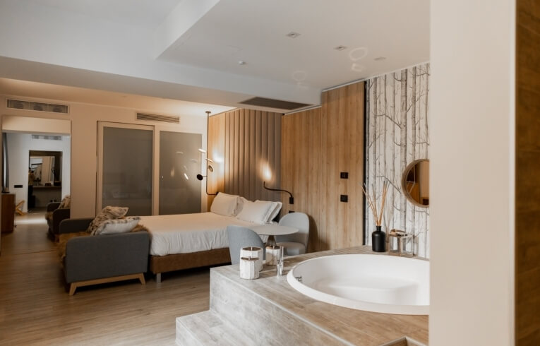 Camera d'hotel con letto, vasca, tavolo e pareti in legno.