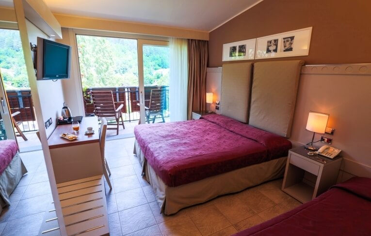 Camera d'hotel con due letti, scrivania e balcone.