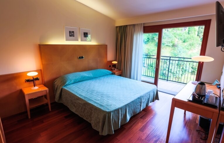 Camera d'hotel con letto, balcone e scrivania attrezzata.
