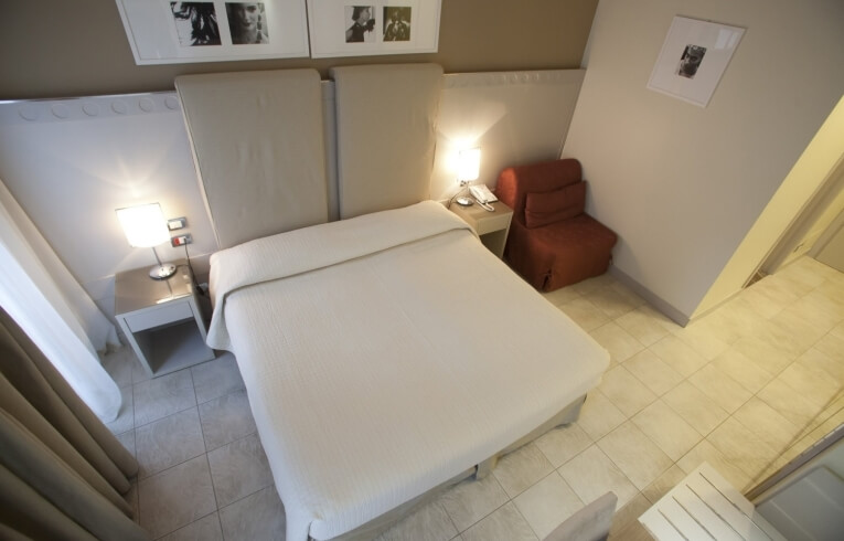 Cozy hotel room with a bed, armchair, and bedside tables.