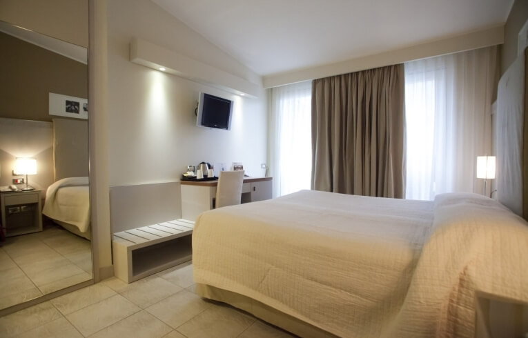 Hotel room with large bed, desk, TV, and mirror.