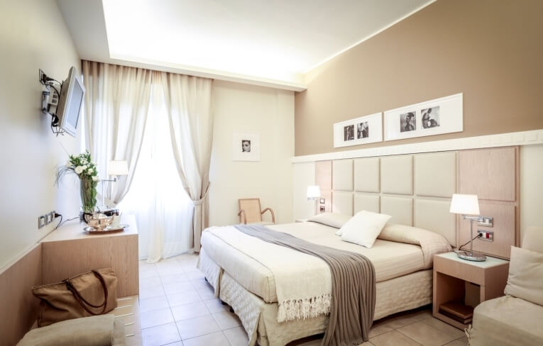 Camera d'hotel con letto, decorazioni floreali e finestra luminosa.