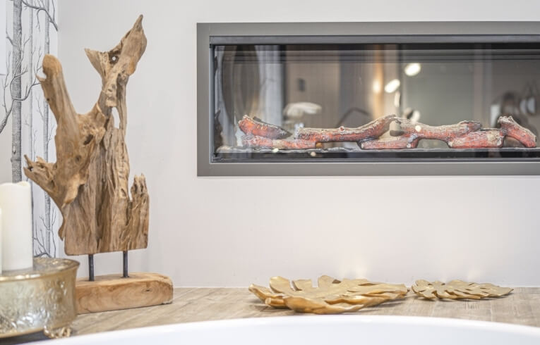Camino con legna artificiale, scultura in legno e piatti decorativi.