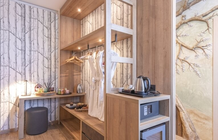 Hotel room with birch tree wallpaper, wardrobe, and decorative shelf.