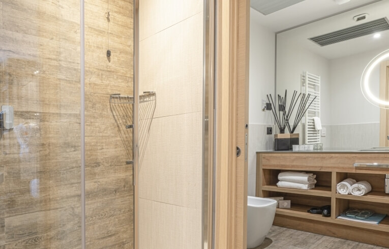 Hotel bathroom with shower, vanity, towels, and personal items.