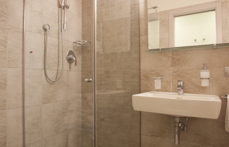 Modern hotel bathroom with tiled walls, shower stall, and sink.