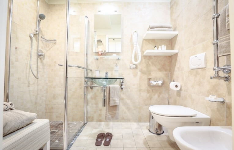 Hotelbadezimmer mit Dusche, Waschbecken, Toilette und Toilettenartikeln.