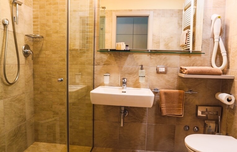 Hotel bathroom featuring a sink, shower, mirror, and toiletries.