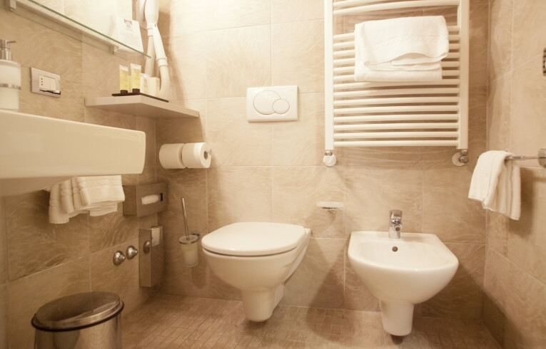 Hotel bathroom with sink, toilet, bidet, and towel racks.