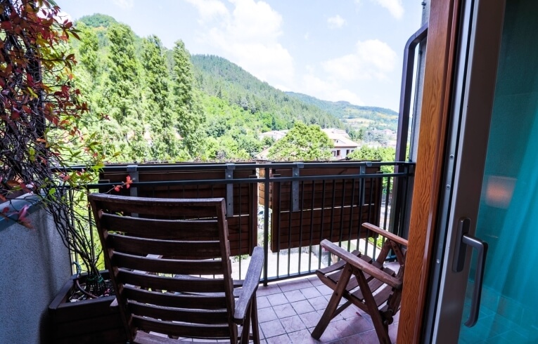 Balkon mit Holzstühlen, Blick auf Tal und Pflanzen.