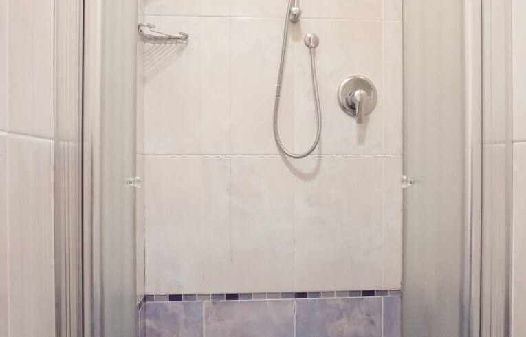 Doccia con porte in vetro smerigliato e parete piastrellata blu e grigia.