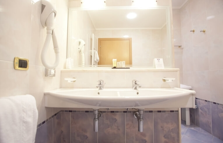 Bagno d'hotel con doppio lavabo, asciugacapelli e prodotti per la cura.
