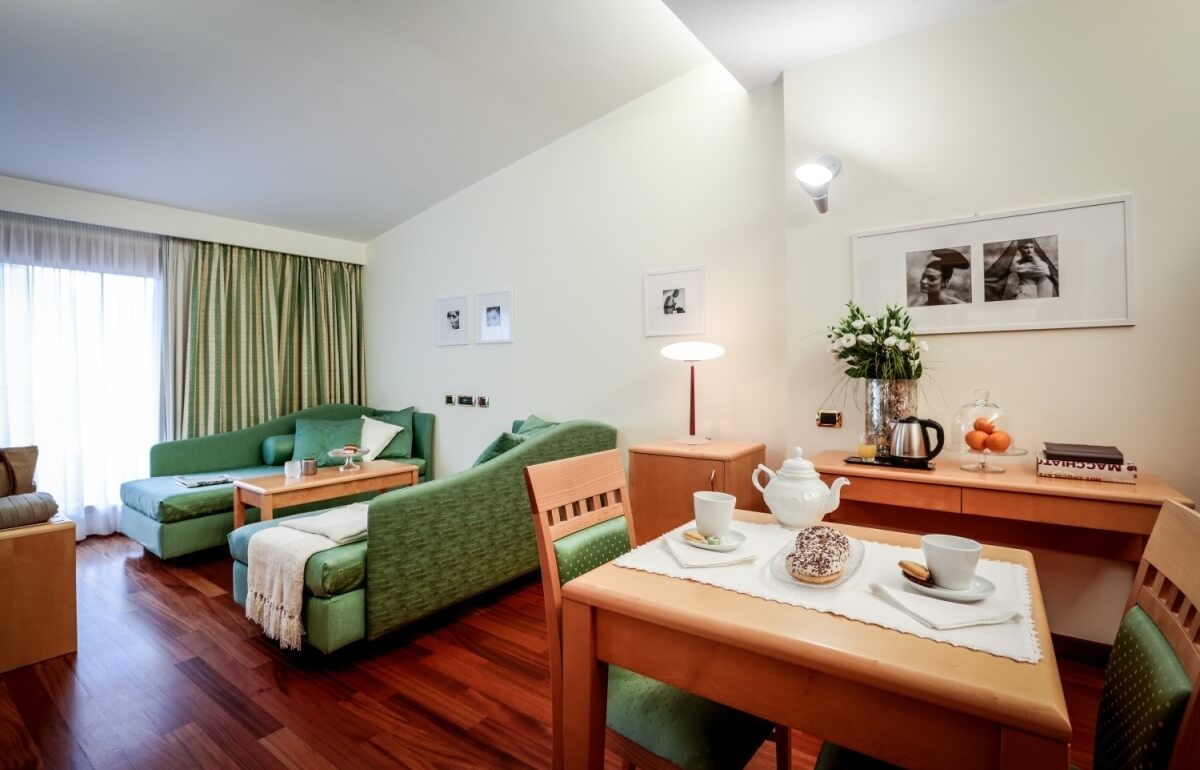 Suite d'hotel con soggiorno, tavolo da pranzo e decorazioni eleganti.
