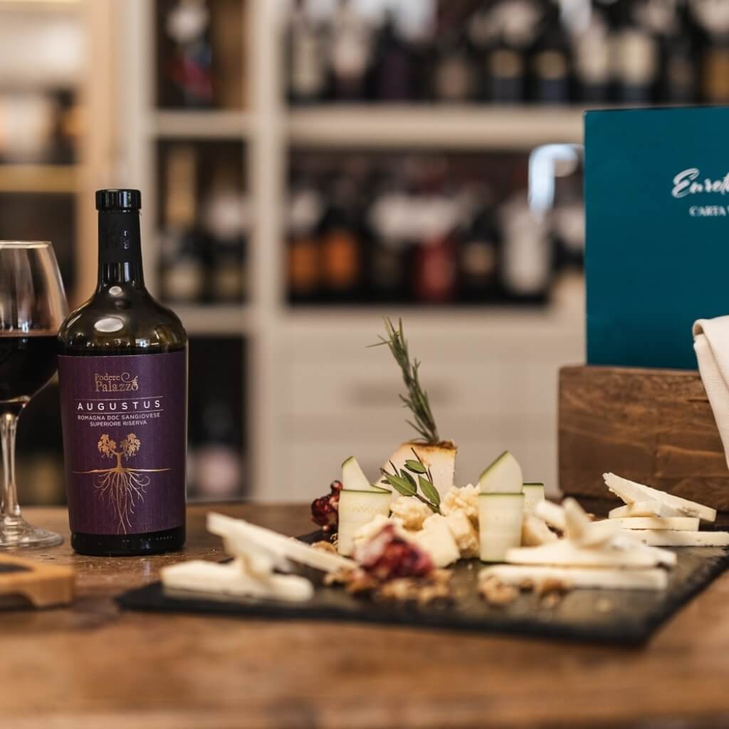 Una bottiglia di vino con un bicchiere e un piatto di formaggi.