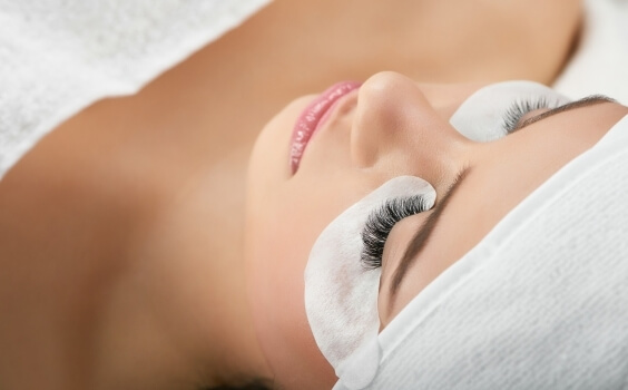 Nahaufnahme eines Gesichts mit Wimpern und Augenpads, Kopf eingewickelt.