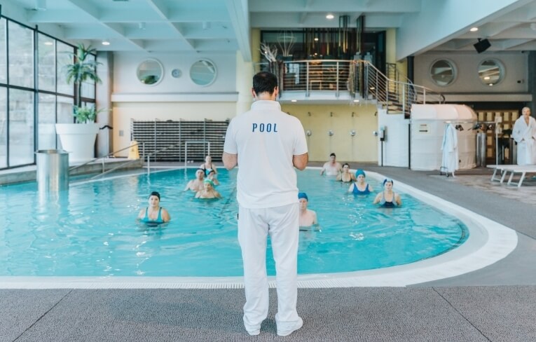 Gruppo di persone che si esercitano in una piscina interna.