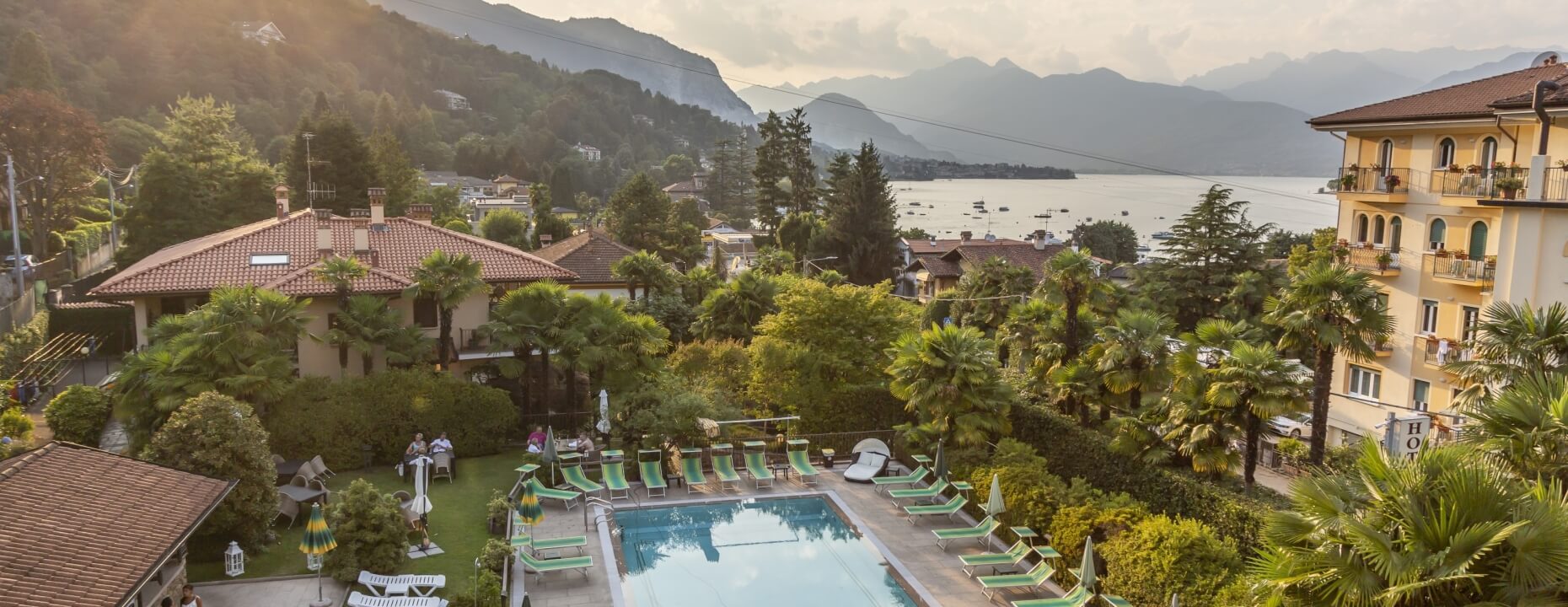 Serene poolside scene with lounge chairs, greenery, mountains, and a sunset sky, evoking relaxation and tranquility.