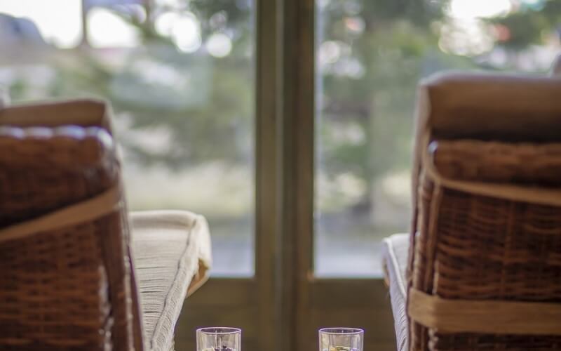 Due cesti in vimini con cinghie beige, posti ai lati di una finestra che offre una vista serena all'esterno.