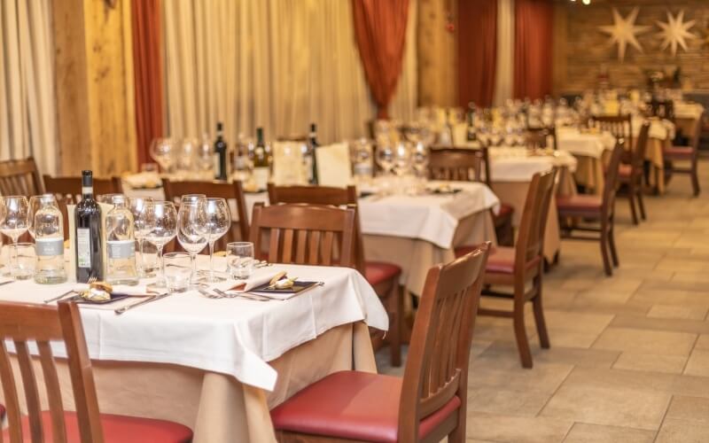 Elegant dining room with white tablecloths, wine glasses, and a stone wall featuring an 8-pointed star, creating a warm ambiance.