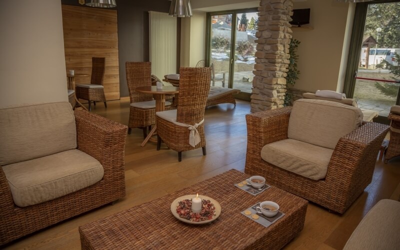 Cozy room with wicker furniture, a coffee table with a candle and potpourri, a stone column, and a fireplace.