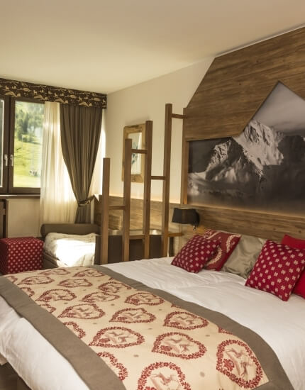 Camera serena con letto grande, testiera in legno, vista su un campo verde e decorazioni in toni naturali.