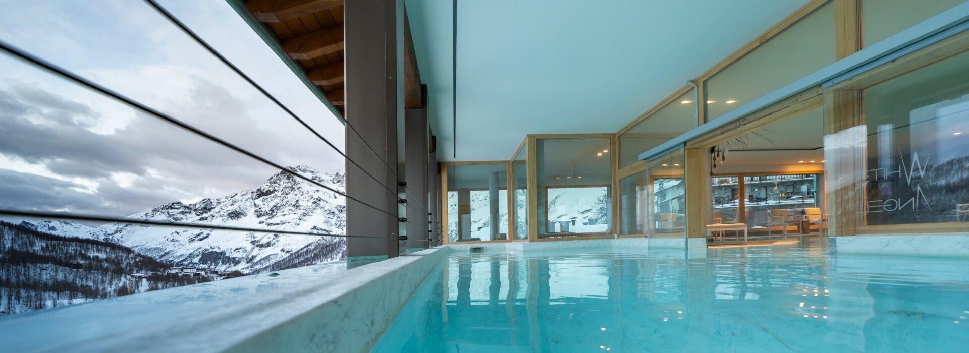 Pool with a mountain view, wooden roof, glass-walled room labeled "WHITE SPACE," and a serene atmosphere.