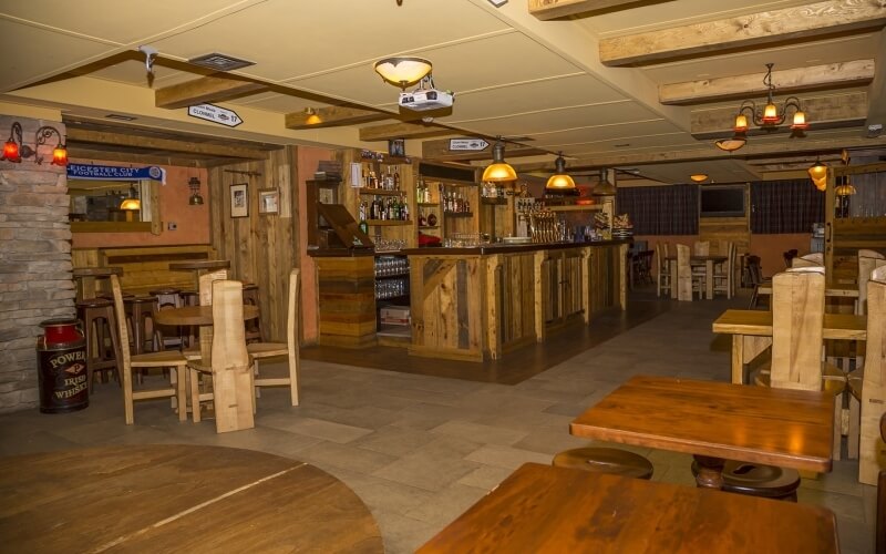 Rustic bar and restaurant with wooden furniture, warm lighting, decorations, and a cozy atmosphere for relaxing evenings.