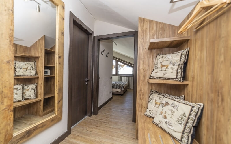 Walk-in closet with a rustic mirror, light wood shelves, whimsical animal print pillows, and a cozy bedroom in the background.