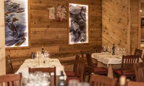 Sala da pranzo rustica e accogliente con tavoli imbanditi, opere d'arte astratte e un elemento decorativo sopra.