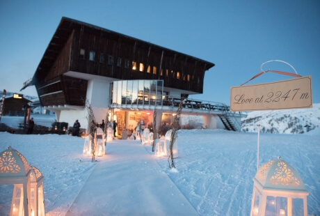 A cozy multi-story building in the snow, with lanterns glowing and a sign reading "Love at 2247 m."