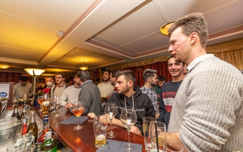 A diverse group of men socialize at a cozy bar, enjoying drinks in a relaxed, informal atmosphere.