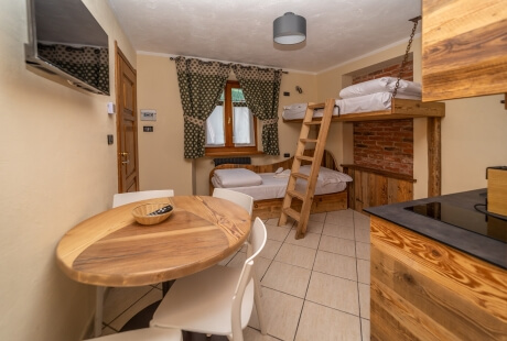 Cozy beige room with bunk beds, wooden table, TV, air conditioning, and green curtains, designed for short-term stays.
