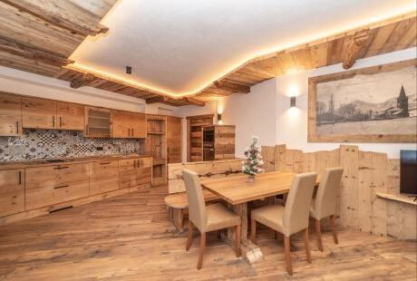 Modern rustic dining room and kitchen with wooden accents, a table, chairs, artwork, and warm lighting.