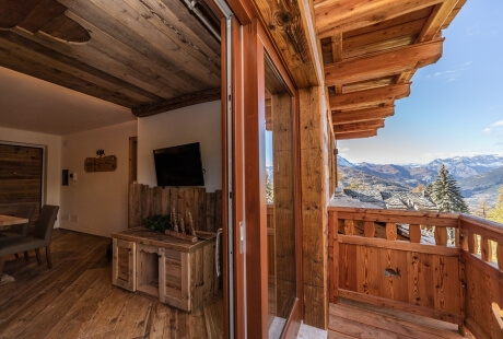 Cozy living space with mountain views, featuring a couch, coffee table, and wooden deck for relaxation.