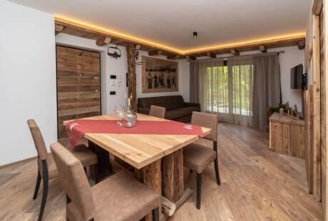 Modern rustic living room and dining area with wooden furniture, natural light, and cozy decor.