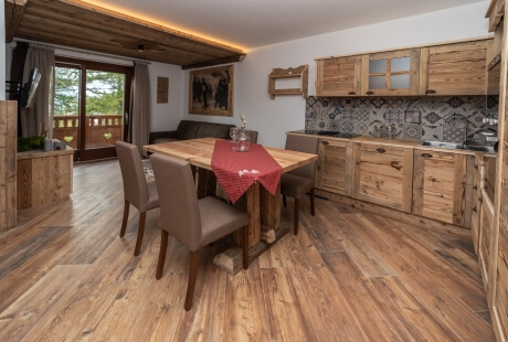 Cozy dining room with wooden table, upholstered chairs, kitchen area, and natural light from sliding doors to the deck.
