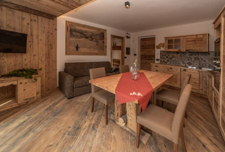 Rustic open-plan living area with wooden accents, a dining table, dark gray couch, and cozy decor.