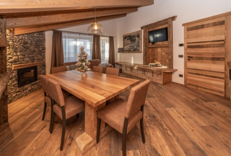 Cozy room with oak features, rustic table, fireplace, and layered curtains, creating a warm, inviting atmosphere.