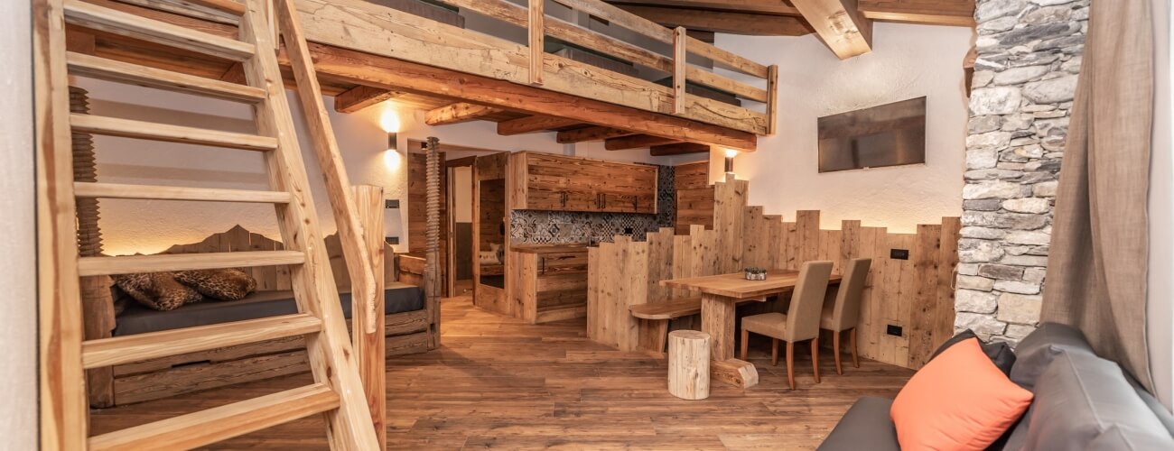 Una stanza rustica e accogliente con un soppalco, un tavolo in legno e un divano, che trasmette calore e comfort.