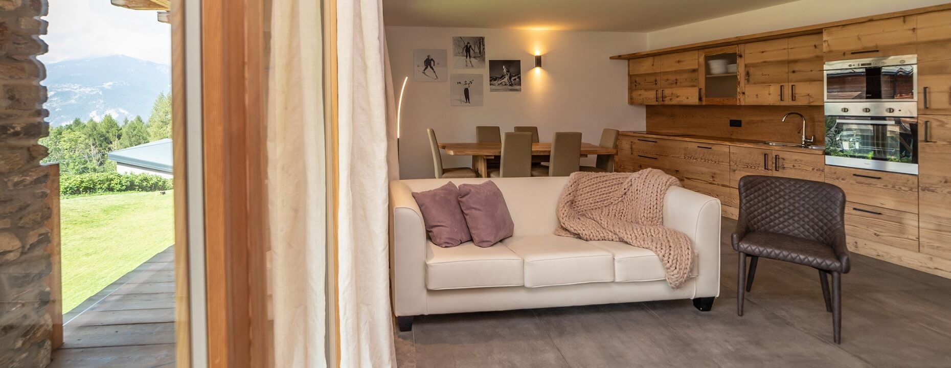 Soggiorno accogliente con divano bianco, cucina moderna e fotografie in bianco e nero su una parete.