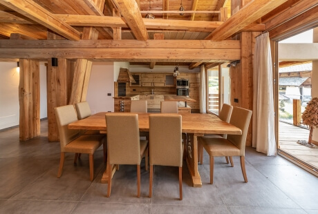 Tavolo in legno elegante con otto sedie in un ambiente raffinato, con travi di cedro e pavimento in cemento lucidato.