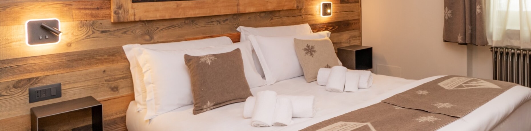 Serene bedroom with a wooden headboard, white bedding, soft lighting, and a cozy ambiance for relaxation.