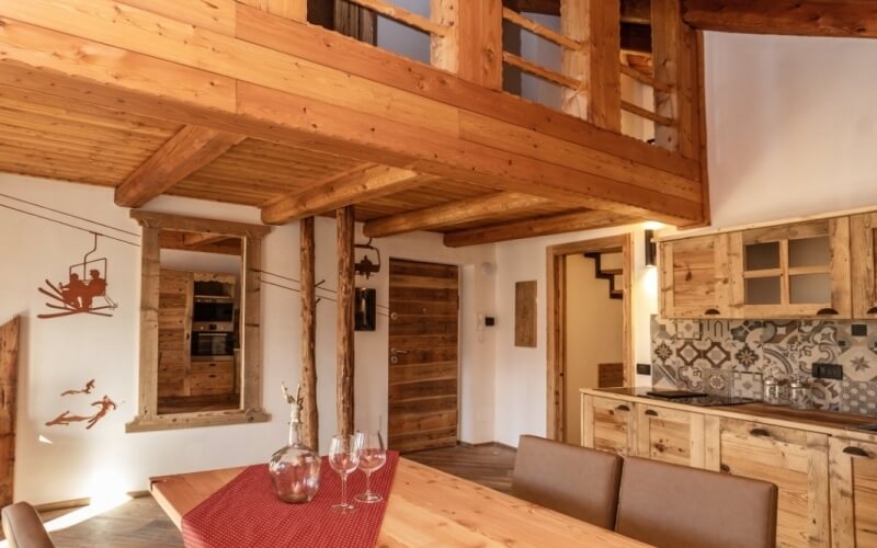 Modern rustic open-plan living space with wooden furniture, natural light, and a loft area.