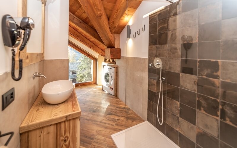 Modern bathroom featuring a shower, oval sink with cabinet, washing machine, and large window for natural light.
