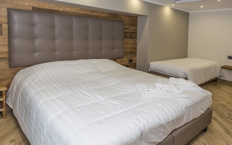 Cozy bedroom with two beds, modern and rustic decor, warm lighting, and a brown color scheme.