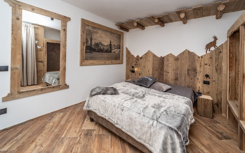 Camera da letto serena con parete a tema montano, letto centrale, gatto che dorme e atmosfera accogliente e tranquilla.