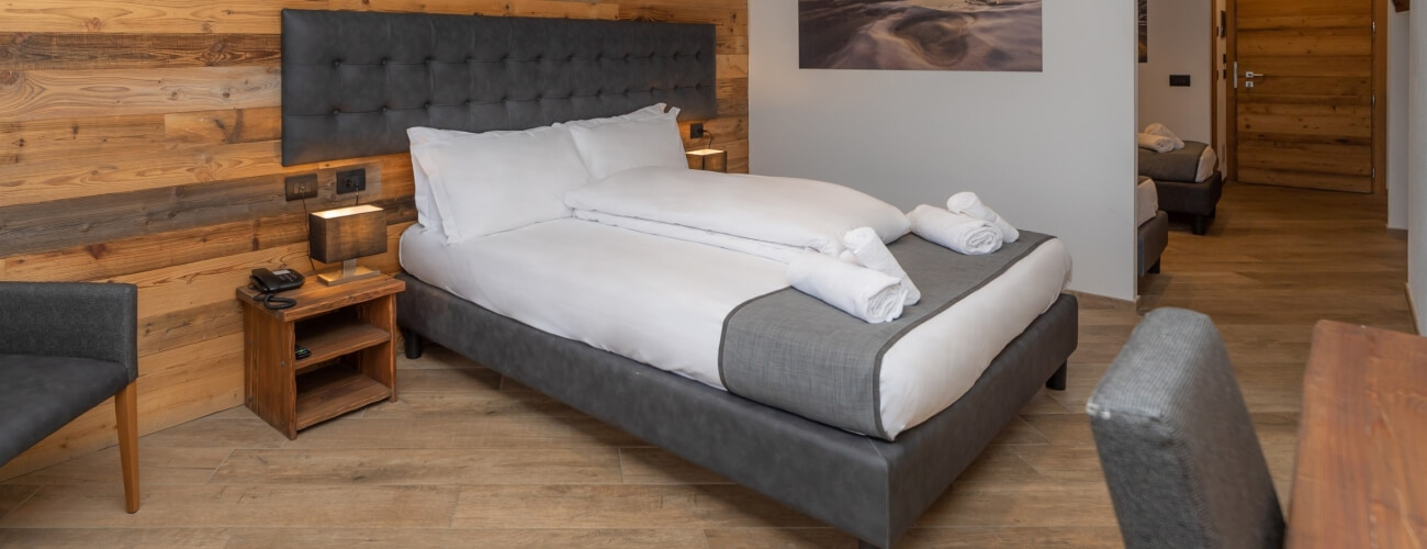 Camera d'hotel serena con letto queen, parete in legno, tavolo e sedia, e atmosfera di relax e comfort.
